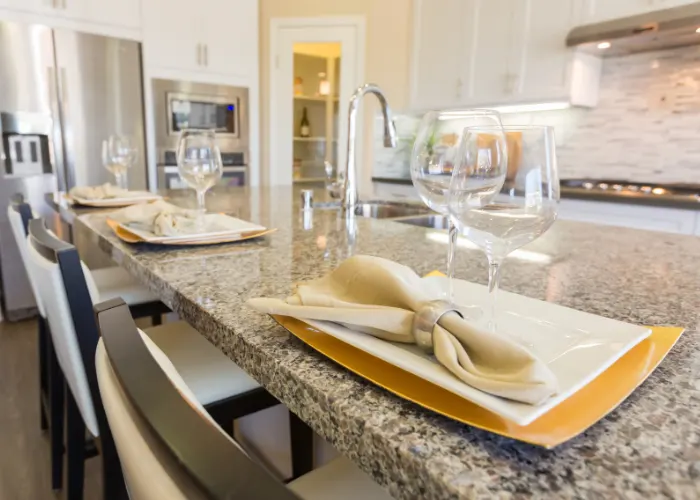 Closeup view of a beautiful granite kitchen countertop with plates and glasses on it